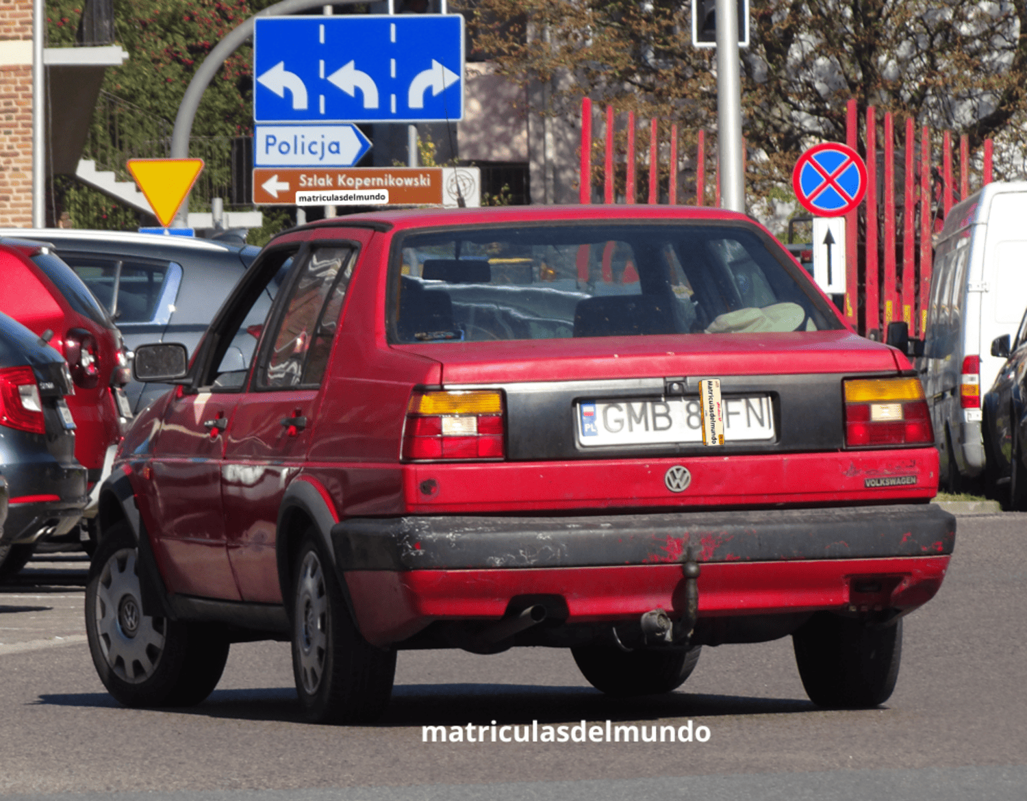 Vista trasera de un Volkswagen Jetta de segunda generación color rojo con una antigua matrícula de Polonia y con bandera en la parte izquierda dando marcha atrás