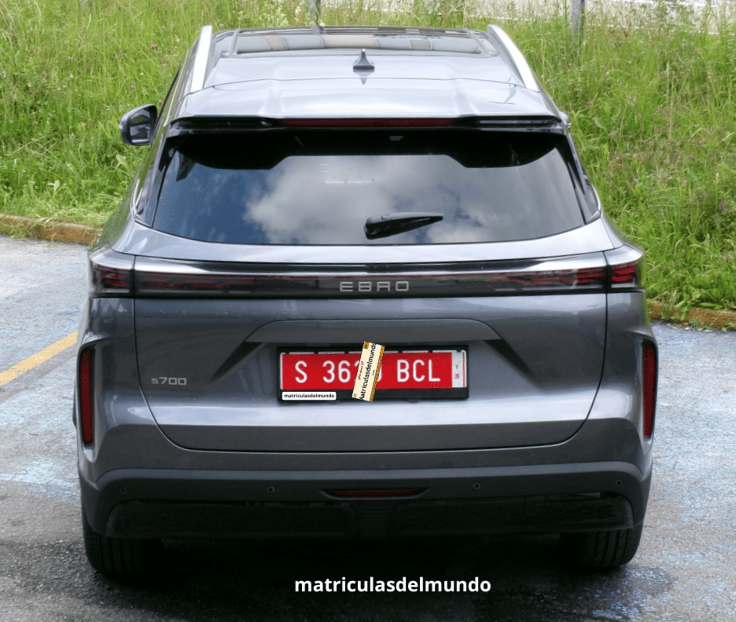 Ebro S700 nuevo de color gris con matrícula roja temporal de concesionario aparcado enfrente de una tienda de Ebro