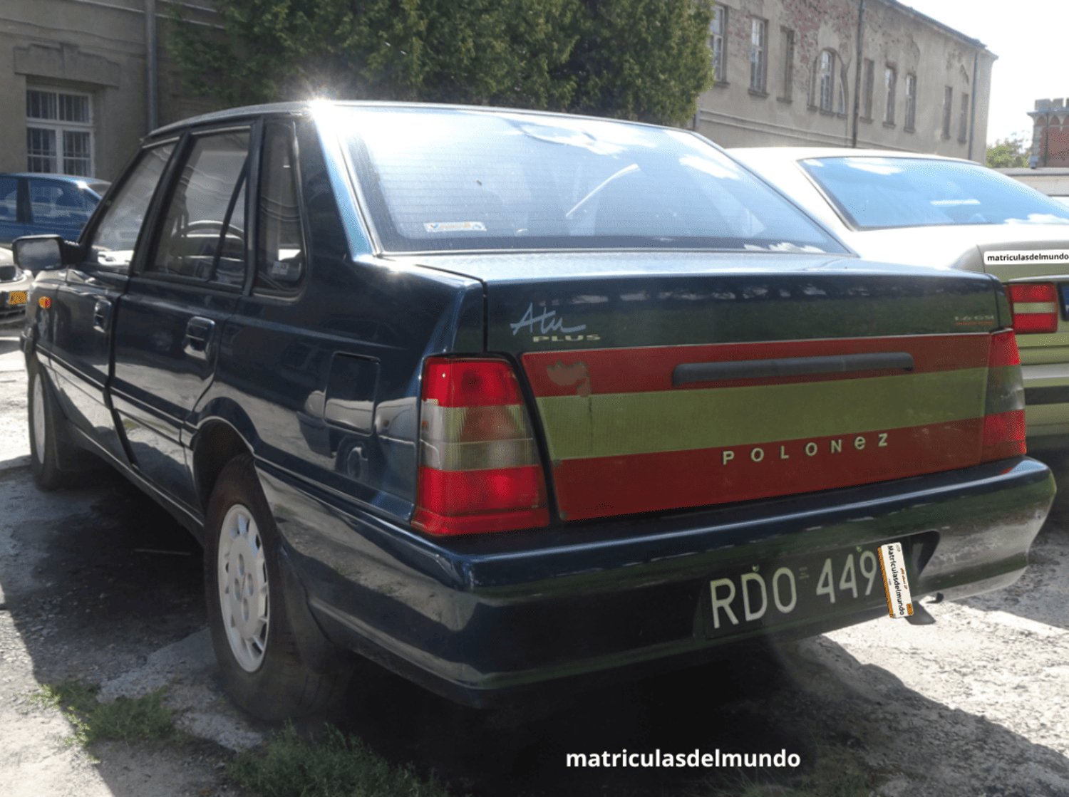 Polonez Atu Plus verde con placa de matriculación negra de Polonia aparcado en una zona industrial junto a otros coches clásicos