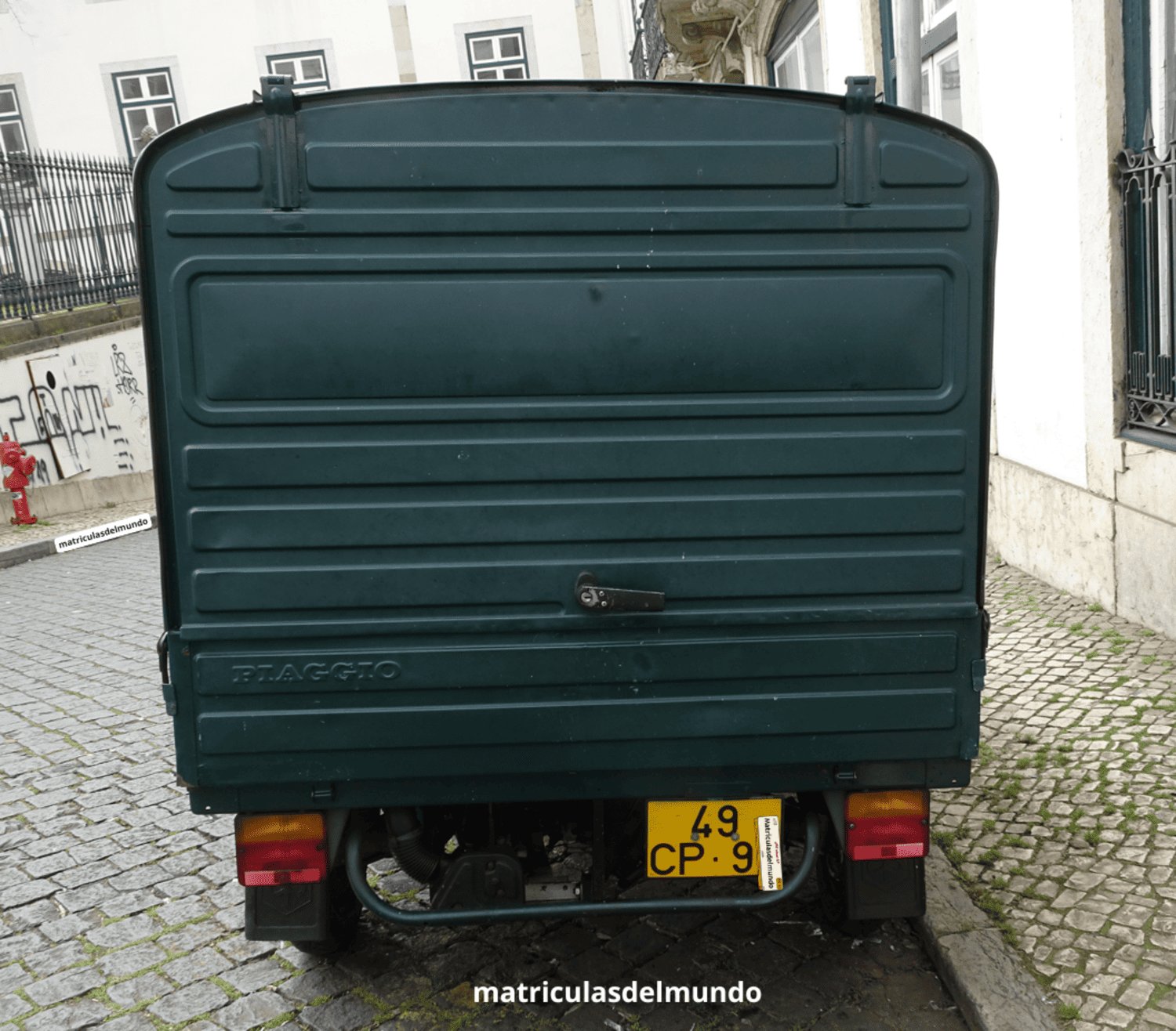 Moto Piaggio furgoneta color verde y con placa de motocicleta amarilla de Portugal aparcada en una calle empedrada de una ciudad turística de Portugal